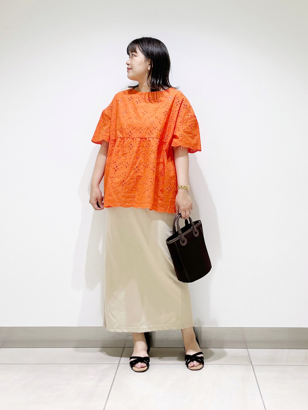 オレンジ系のシャツ/ブラウス、ブラウン系のショルダーバッグ、ベージュ系のスカートを着用したレディースの夏コーディネートの2枚目の写真