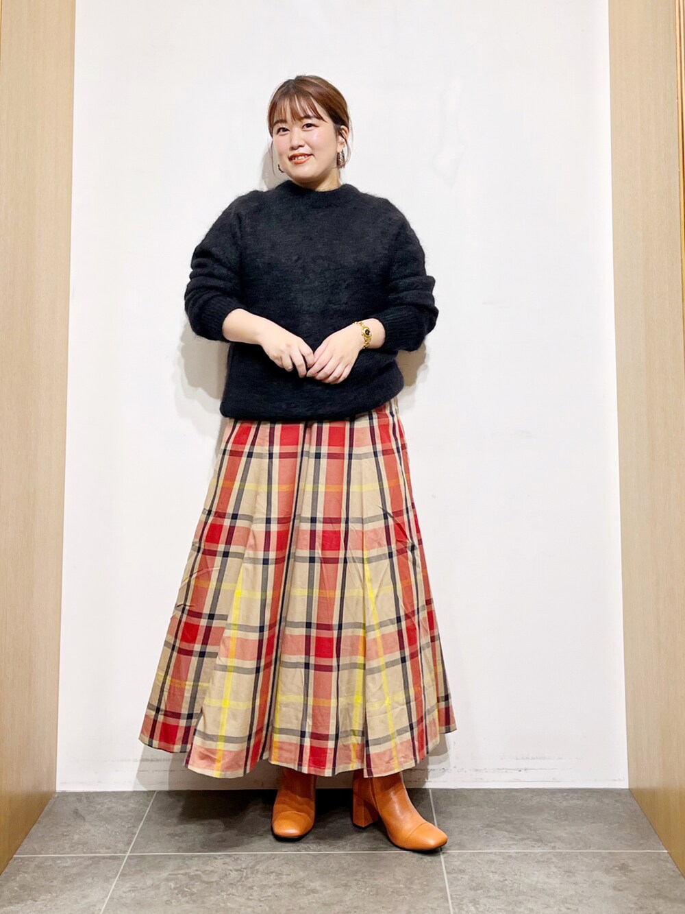 ブラック系のニット/セーター、ベージュ系のスカート、ピンク系のブーツを着用したレディースの秋コーディネートの4枚目の写真