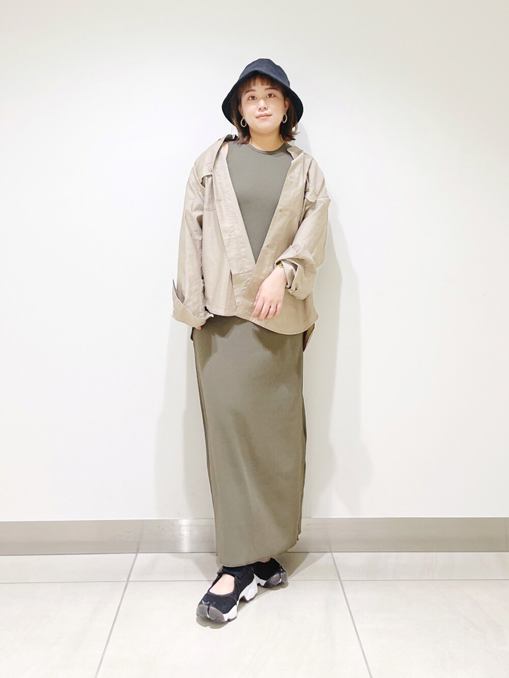 グリーン系のワンピース、ベージュ系のシャツ/ブラウス、ブラック系のスニーカーを着用したレディースの春コーディネートの2枚目の写真