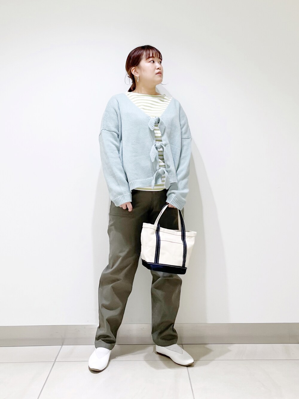 グリーン系のカーディガン/ボレロ、ブルー系のトートバッグ、ホワイト系のパンプスを着用したレディースの冬コーディネートの3枚目の写真