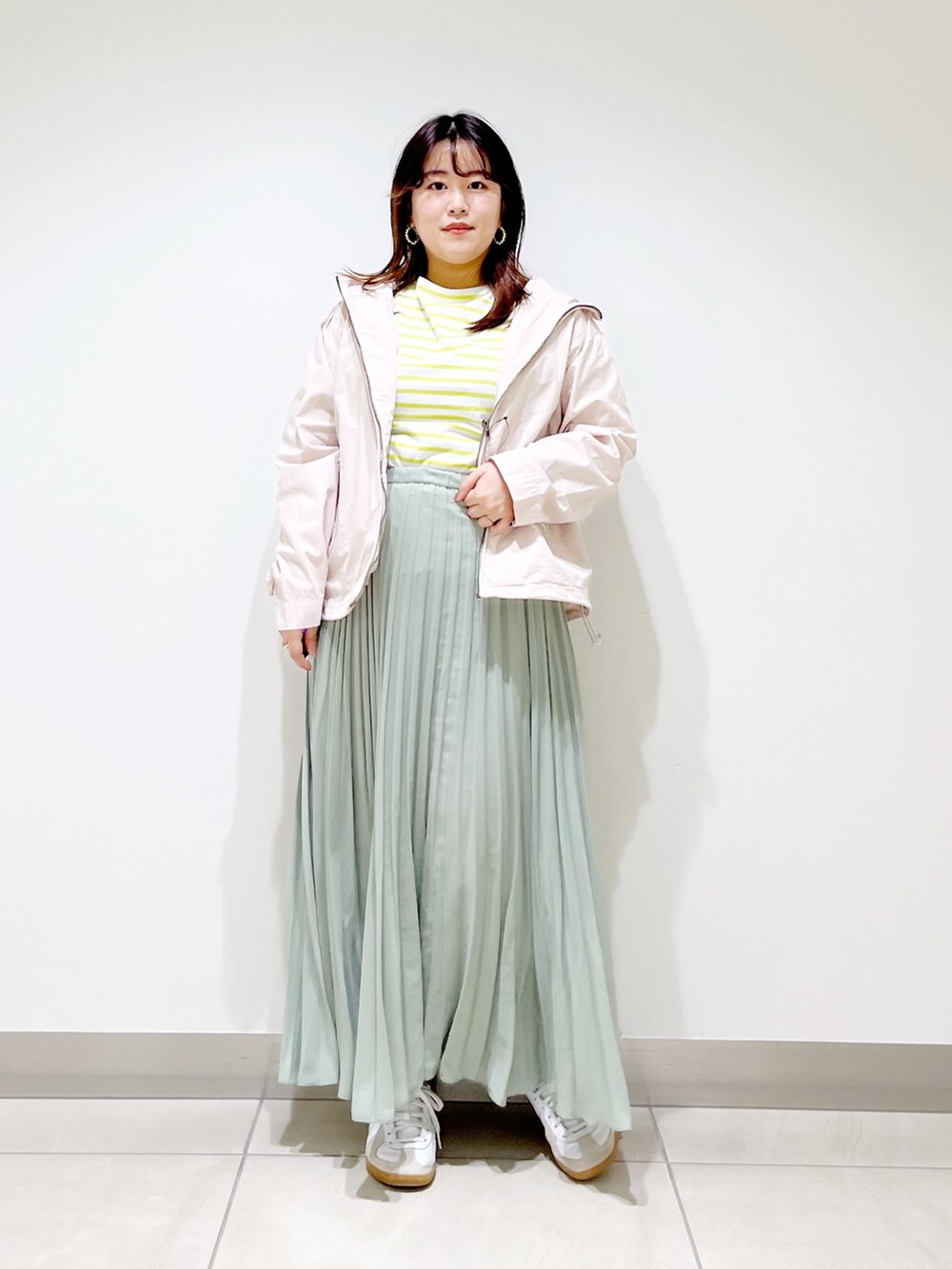 ベージュ系のブルゾン、イエロー系のTシャツ/カットソー、グリーン系のスカートを着用したレディースの春コーディネートの5枚目の写真