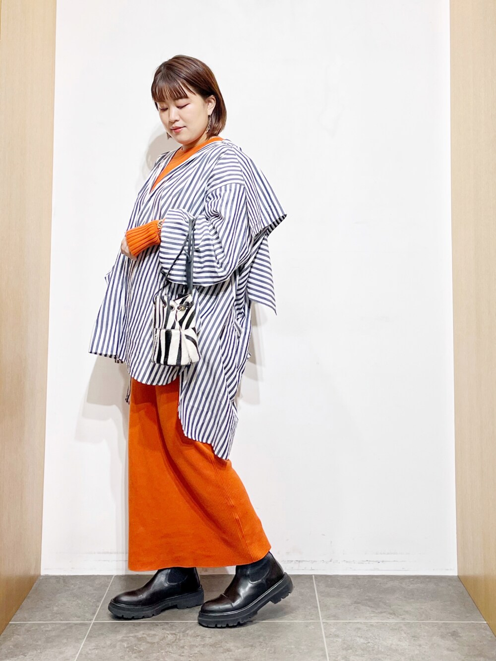 ブルー系のシャツ/ブラウス、オレンジ系のワンピース、ブラック系のブーツを着用したレディースの冬コーディネートの4枚目の写真