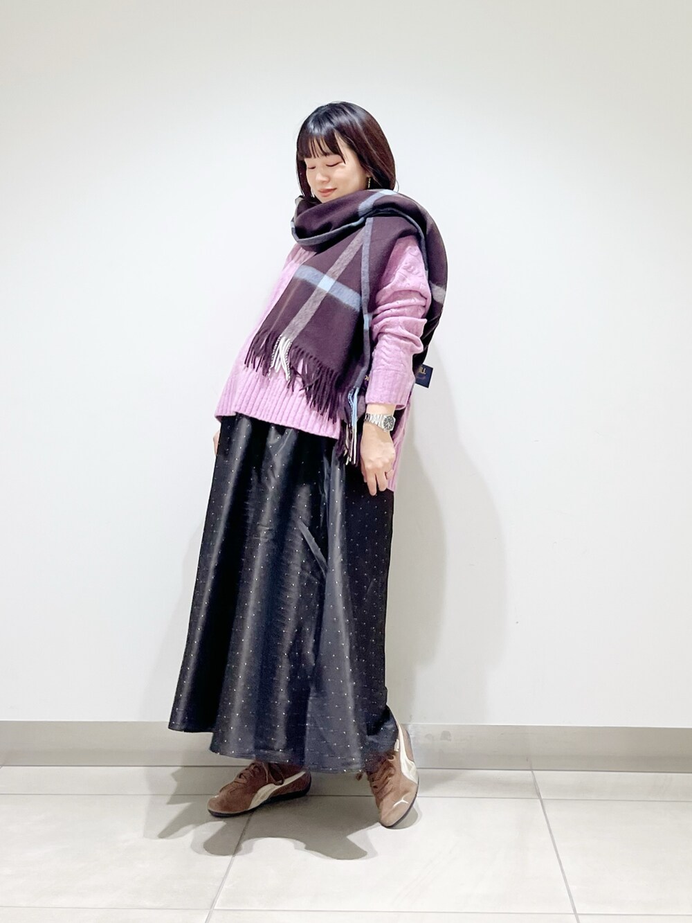 パープル系のニット/セーター、ブルー系のスカート、ブラック系のスニーカーを着用したレディースの秋コーディネートの5枚目の写真