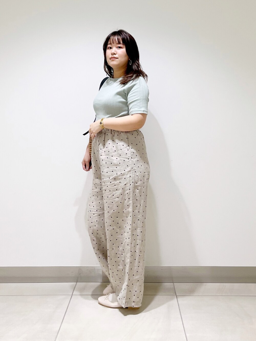 グリーン系のTシャツ/カットソー、ベージュ系のその他パンツ、ブラウン系のバッグを着用したレディースの春コーディネートの5枚目の写真