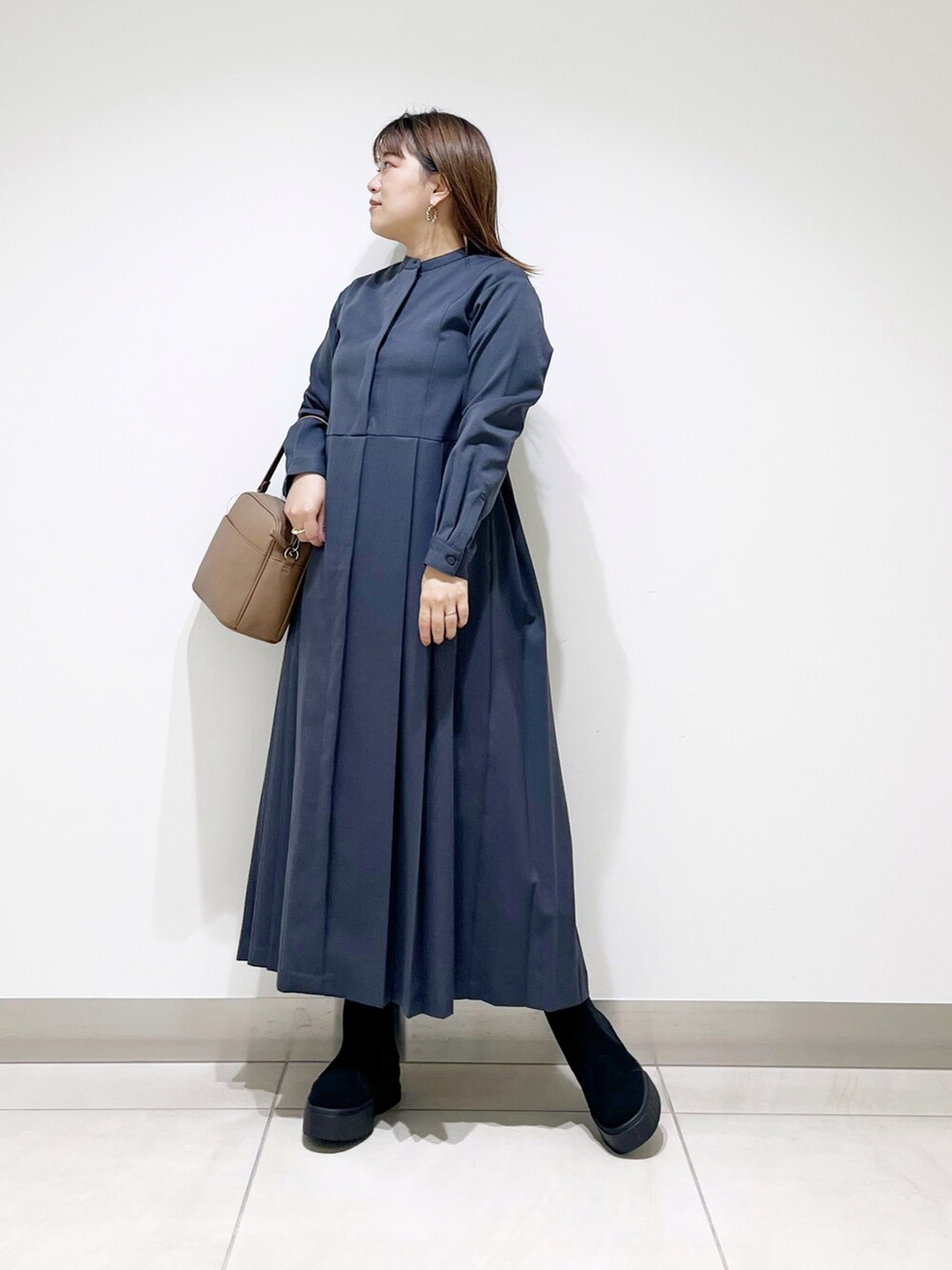 グレー系のワンピース、ブラウン系のショルダーバッグ、ブラック系のブーツを着用したレディースの秋コーディネートの5枚目の写真