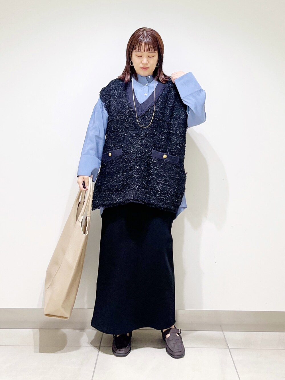 ブルー系のシャツ/ブラウス、ブラック系のスカート、ゴールド系のトートバッグを着用したレディースの秋コーディネートの9枚目の写真