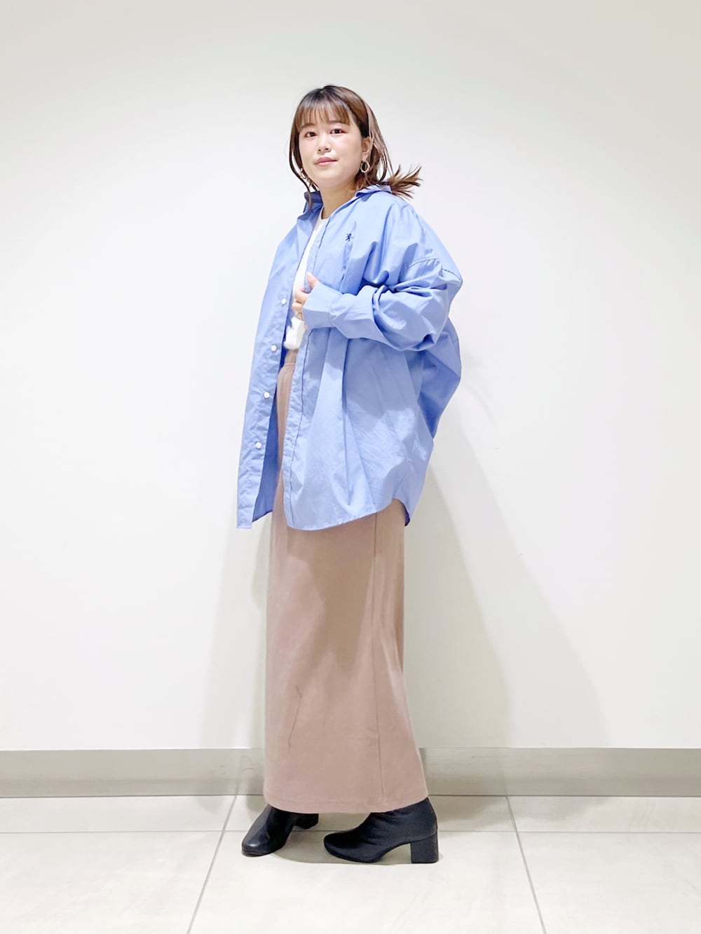 ブルー系のシャツ/ブラウス、ベージュ系のスカート、ブラック系のブーツを着用したレディースの秋コーディネートの2枚目の写真