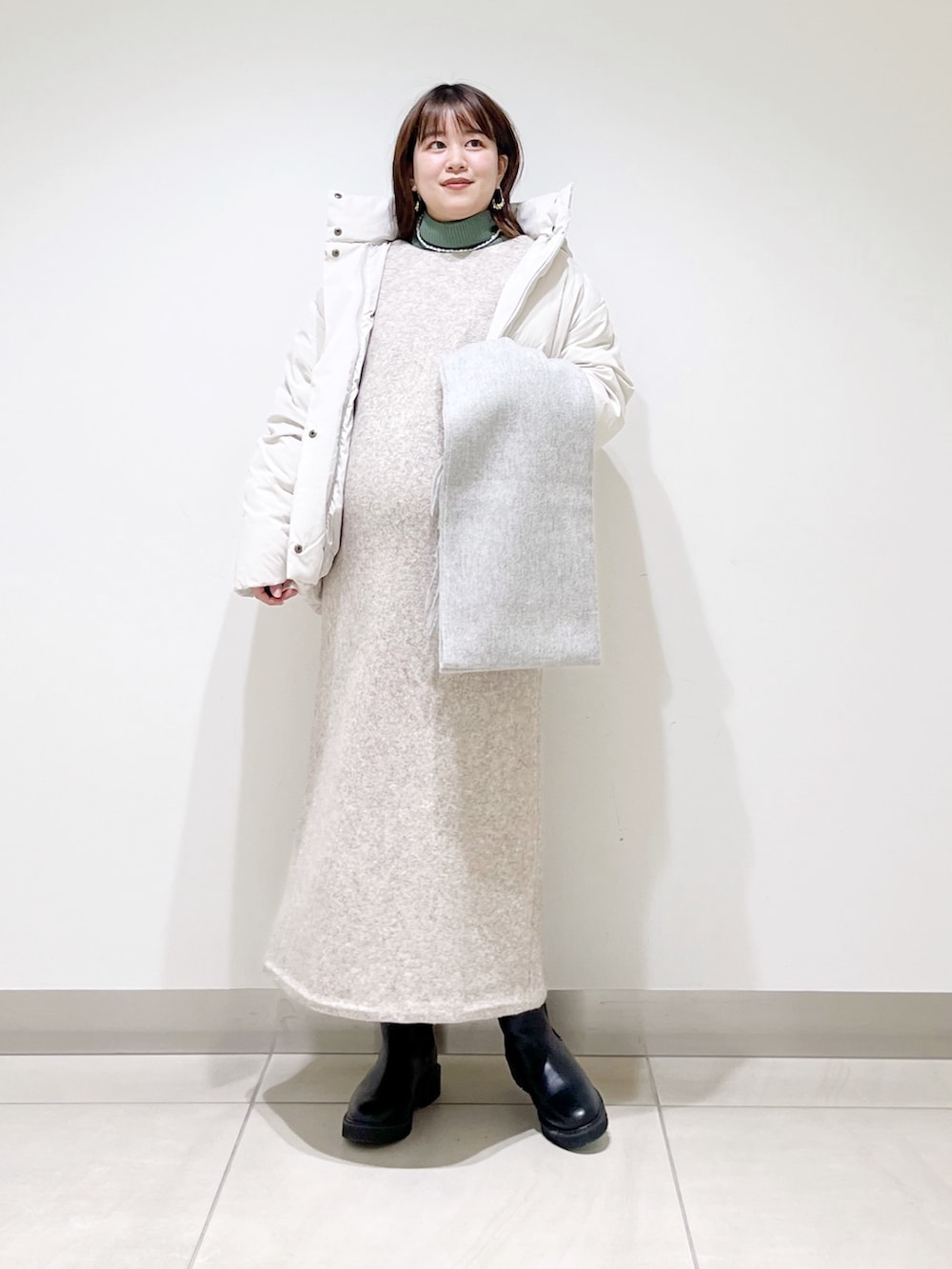 ホワイト系のダウンジャケット/コート、ベージュ系のワンピース、グリーン系のニット/セーターを着用したレディースの冬コーディネートの3枚目の写真