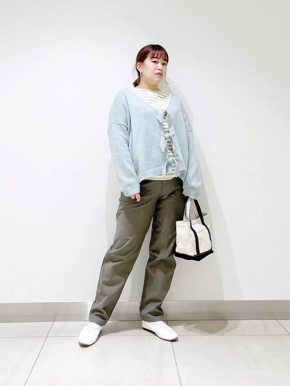 グリーン系のカーディガン/ボレロ、ブルー系のトートバッグ、ホワイト系のパンプスを着用したレディースの冬コーディネートの4枚目の写真