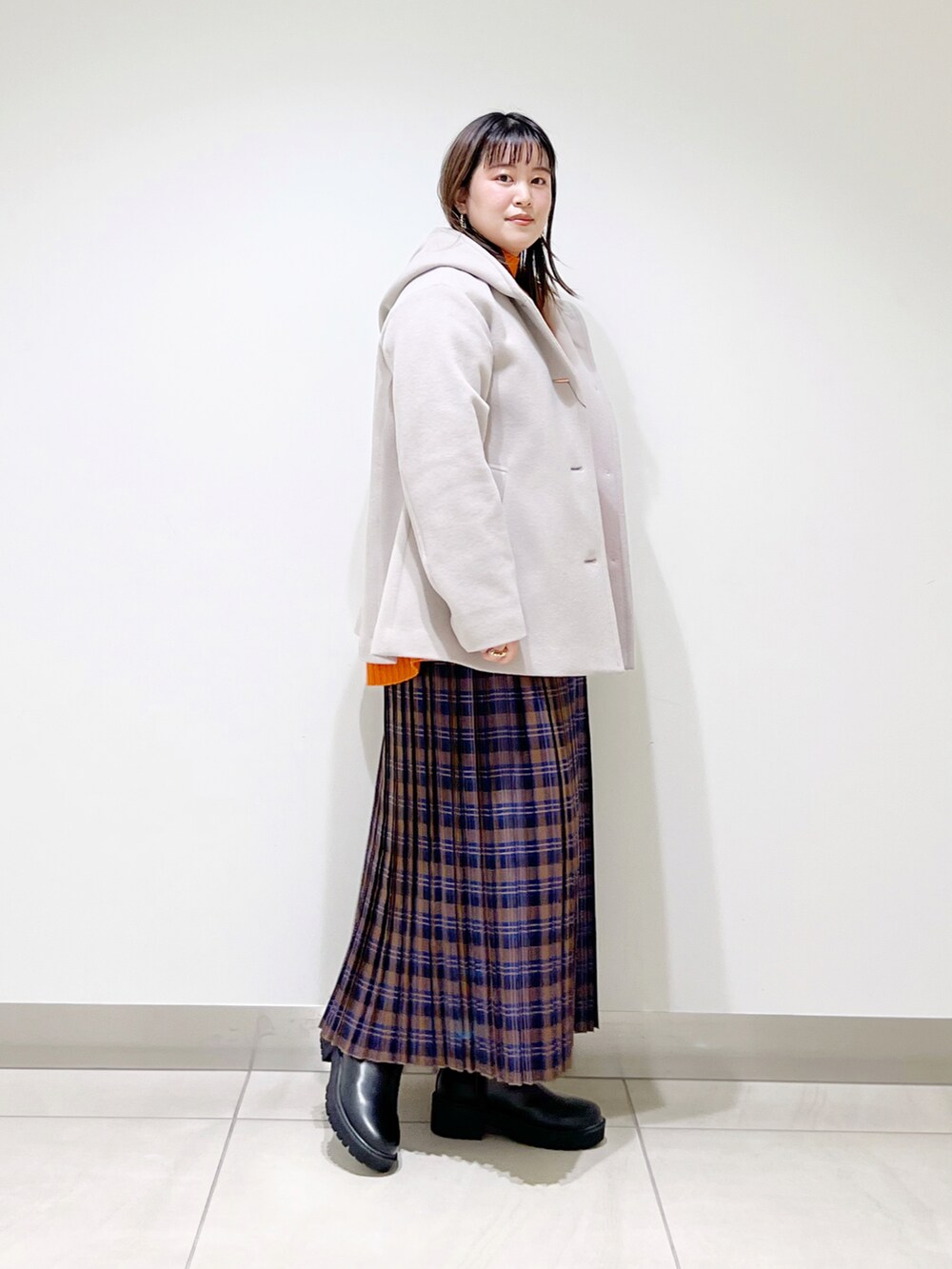 ベージュ系のその他アウター、オレンジ系のニット/セーター、ブルー系のスカートを着用したレディースの秋コーディネートの3枚目の写真