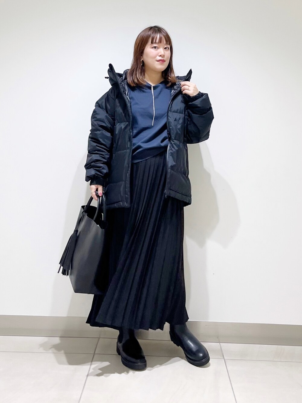 ブラック系のダウンジャケット/コート、ブルー系のTシャツ/カットソー、ブラック系のスカートを着用したレディースの秋コーディネートの7枚目の写真