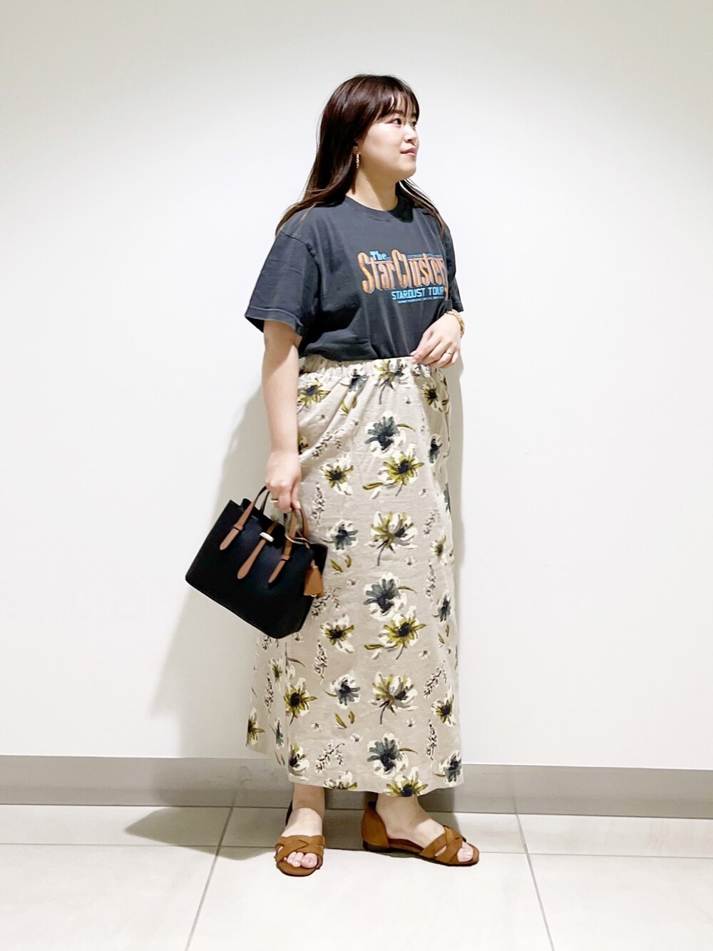 オレンジ系のTシャツ/カットソー、ブラック系のハンドバッグ、イエロー系のスカートを着用したレディースの夏コーディネートの3枚目の写真