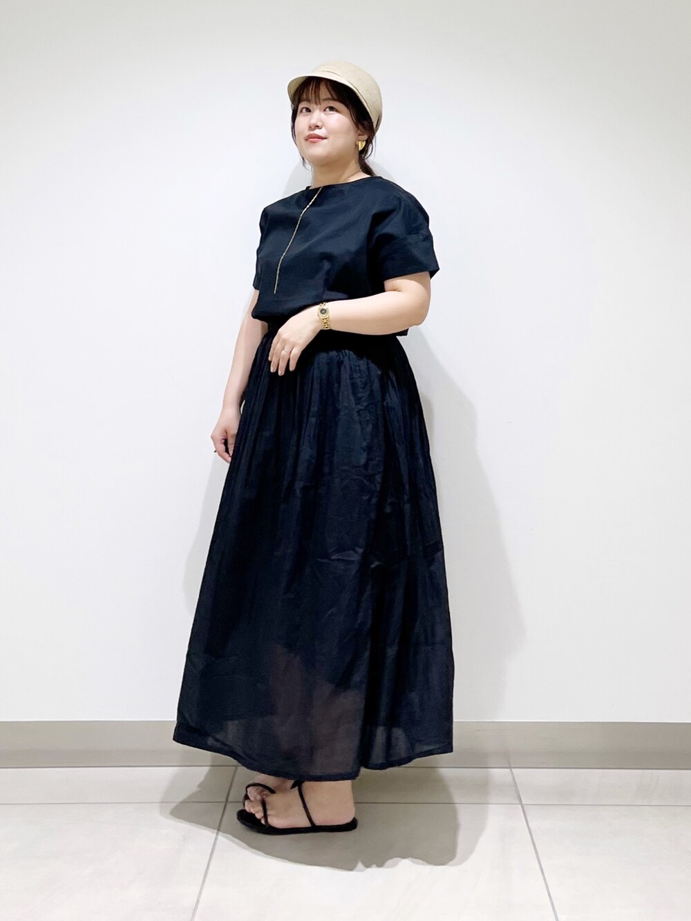 ブラック系のワンピース、ブラック系のサンダル、ベージュ系のキャスケットを着用したレディースの夏コーディネートの5枚目の写真