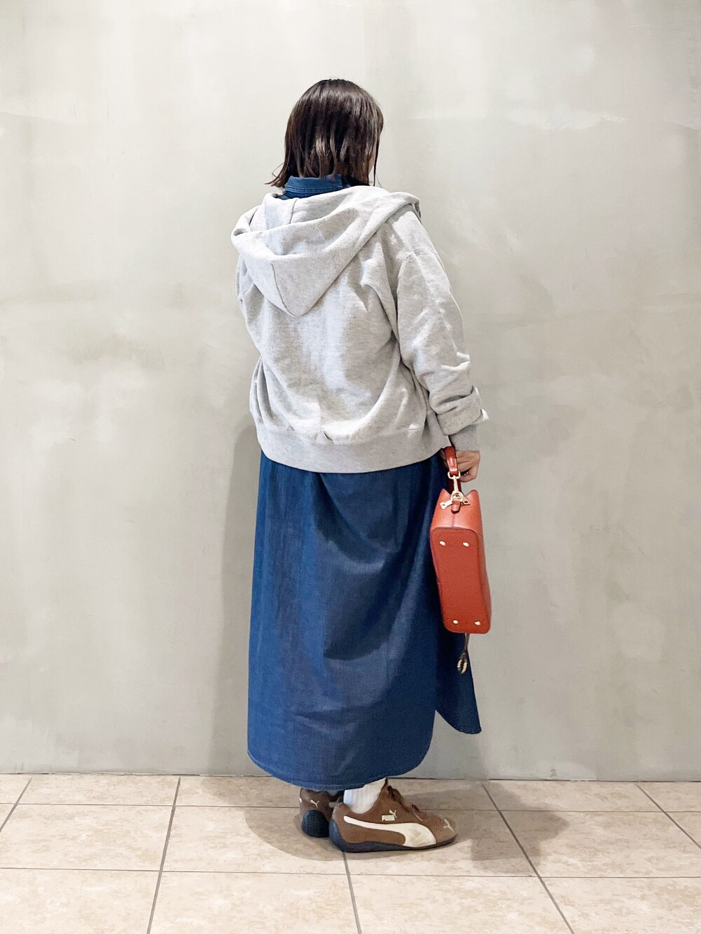 ブルー系のワンピース、オレンジ系のショルダーバッグ、ブラック系のスニーカーを着用したレディースの秋コーディネートの5枚目の写真