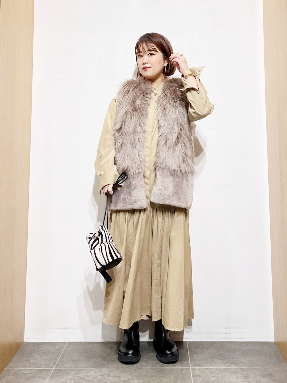 ベージュ系のベスト、ベージュ系のワンピース、その他のバッグを着用したレディースの秋コーディネートの3枚目の写真