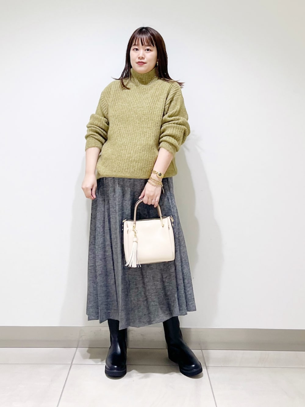 グリーン系のニット/セーター、ブルー系のスカート、ホワイト系のトートバッグを着用したレディースの冬コーディネートの2枚目の写真