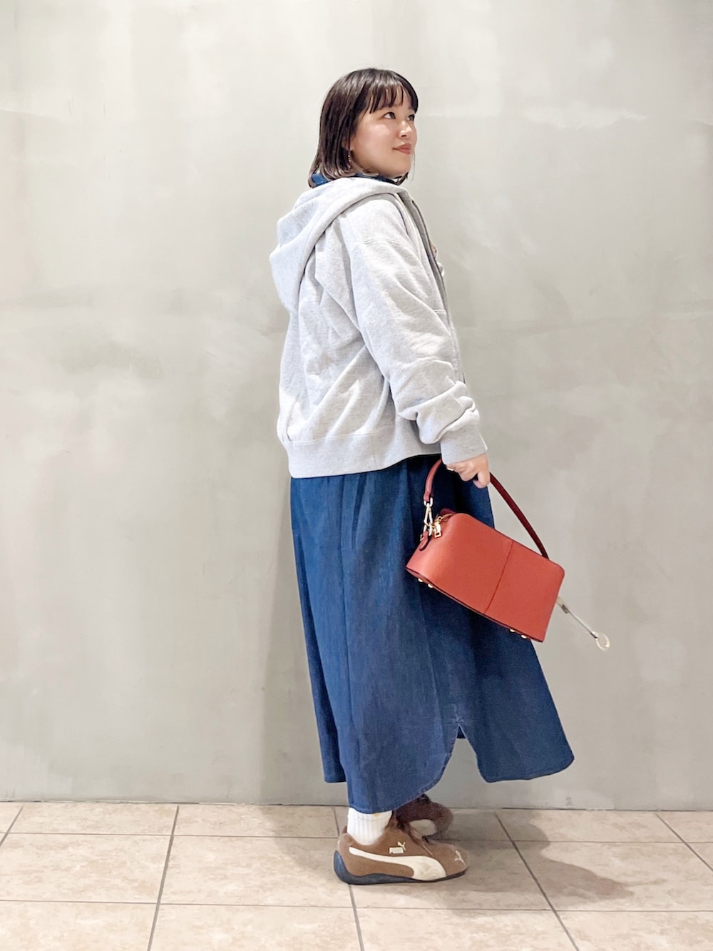 ブルー系のワンピース、オレンジ系のショルダーバッグ、ブラック系のスニーカーを着用したレディースの秋コーディネートの6枚目の写真