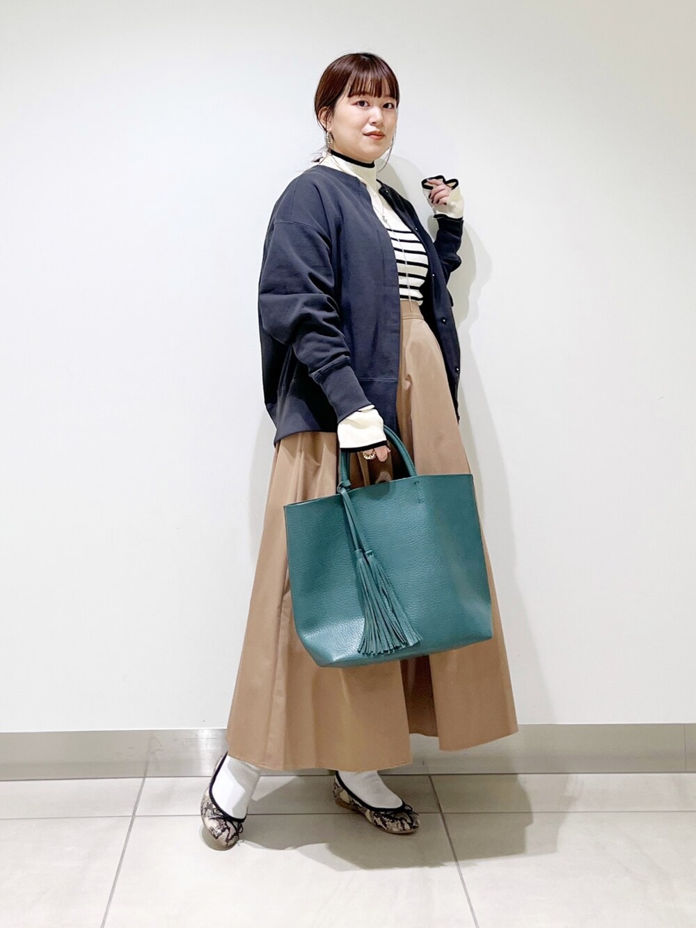 グリーン系のトートバッグ、ベージュ系のスカート、その他のバレエシューズを着用したレディースの秋コーディネートの8枚目の写真