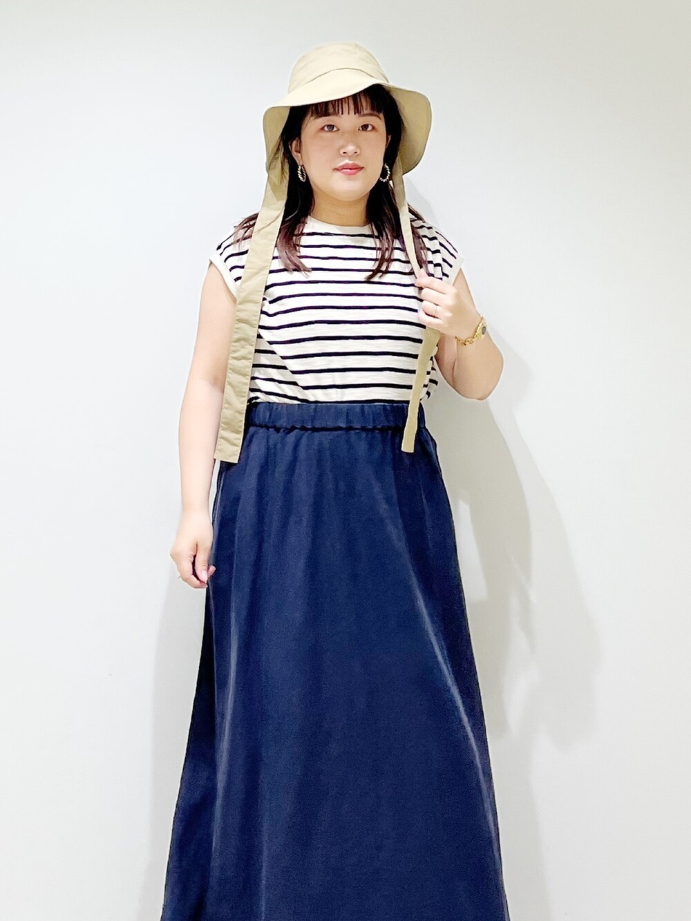 ベージュ系のTシャツ/カットソー、ブルー系のスカート、ベージュ系のサンダルを着用したレディースの夏コーディネートの4枚目の写真