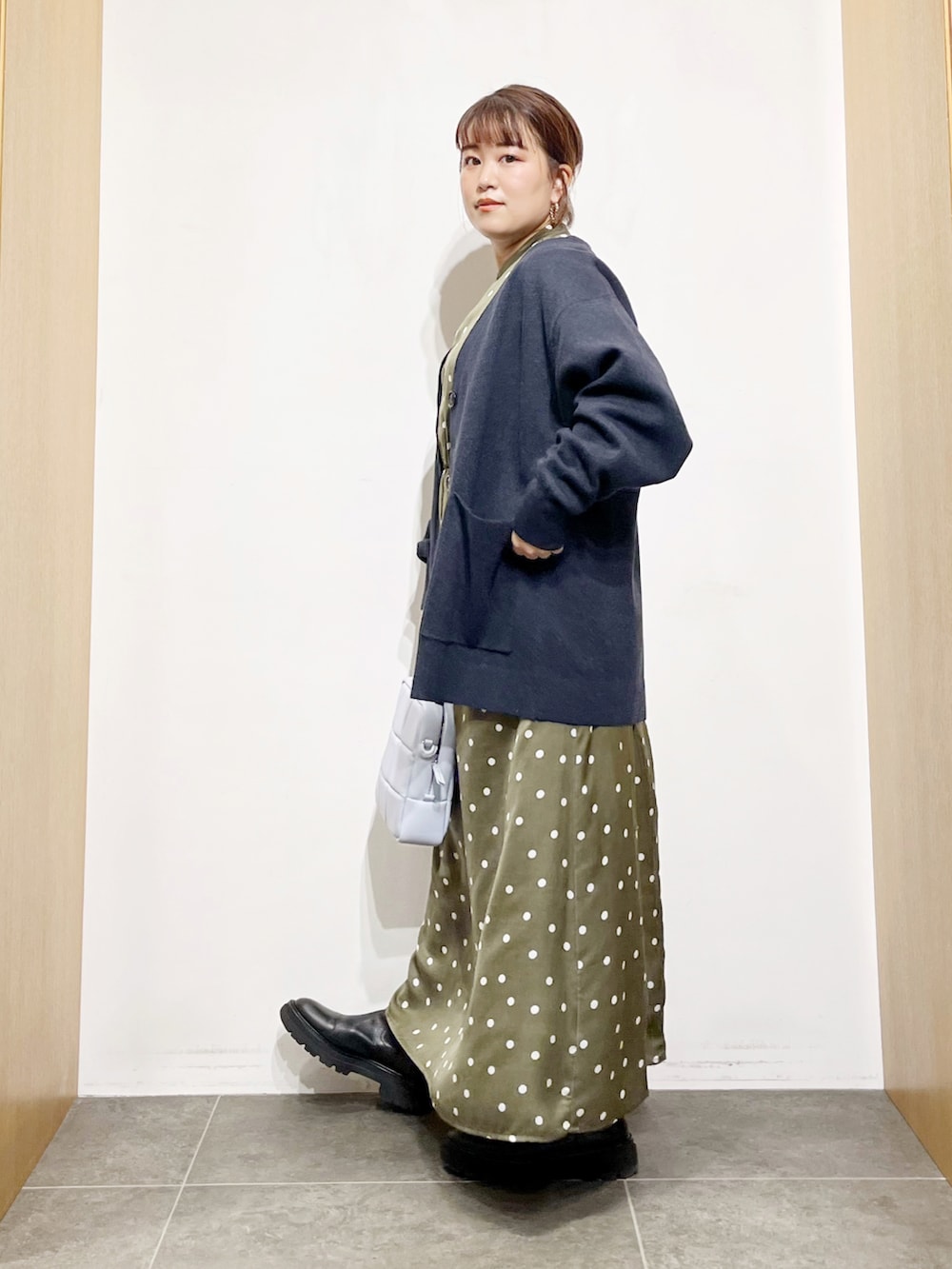 ブルー系のカーディガン/ボレロ、グリーン系のワンピース、ブルー系のハンドバッグを着用したレディースの冬コーディネートの2枚目の写真