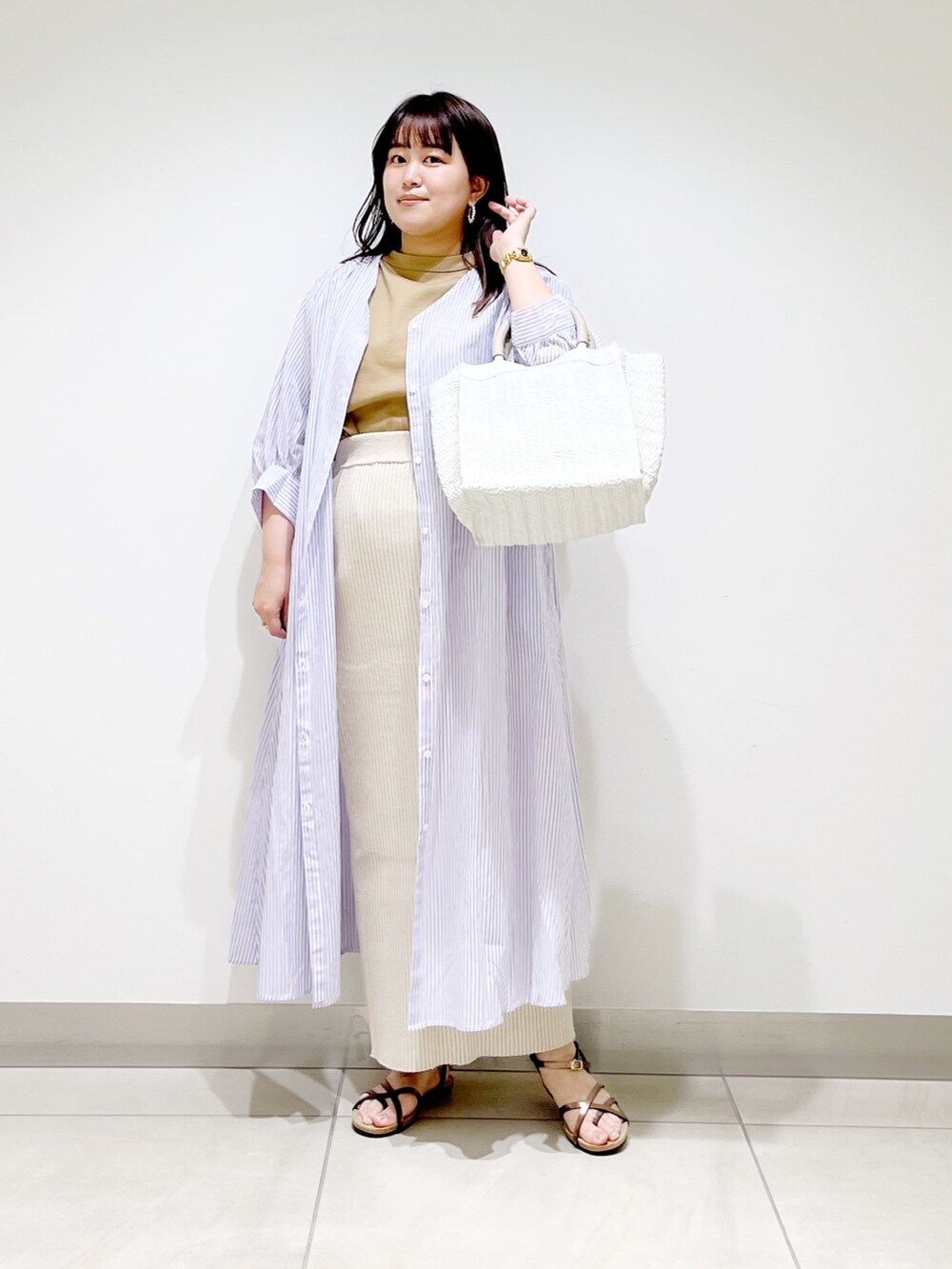 ベージュ系のTシャツ/カットソー、ベージュ系のスカート、パープル系のワンピースを着用したレディースの春コーディネートの5枚目の写真