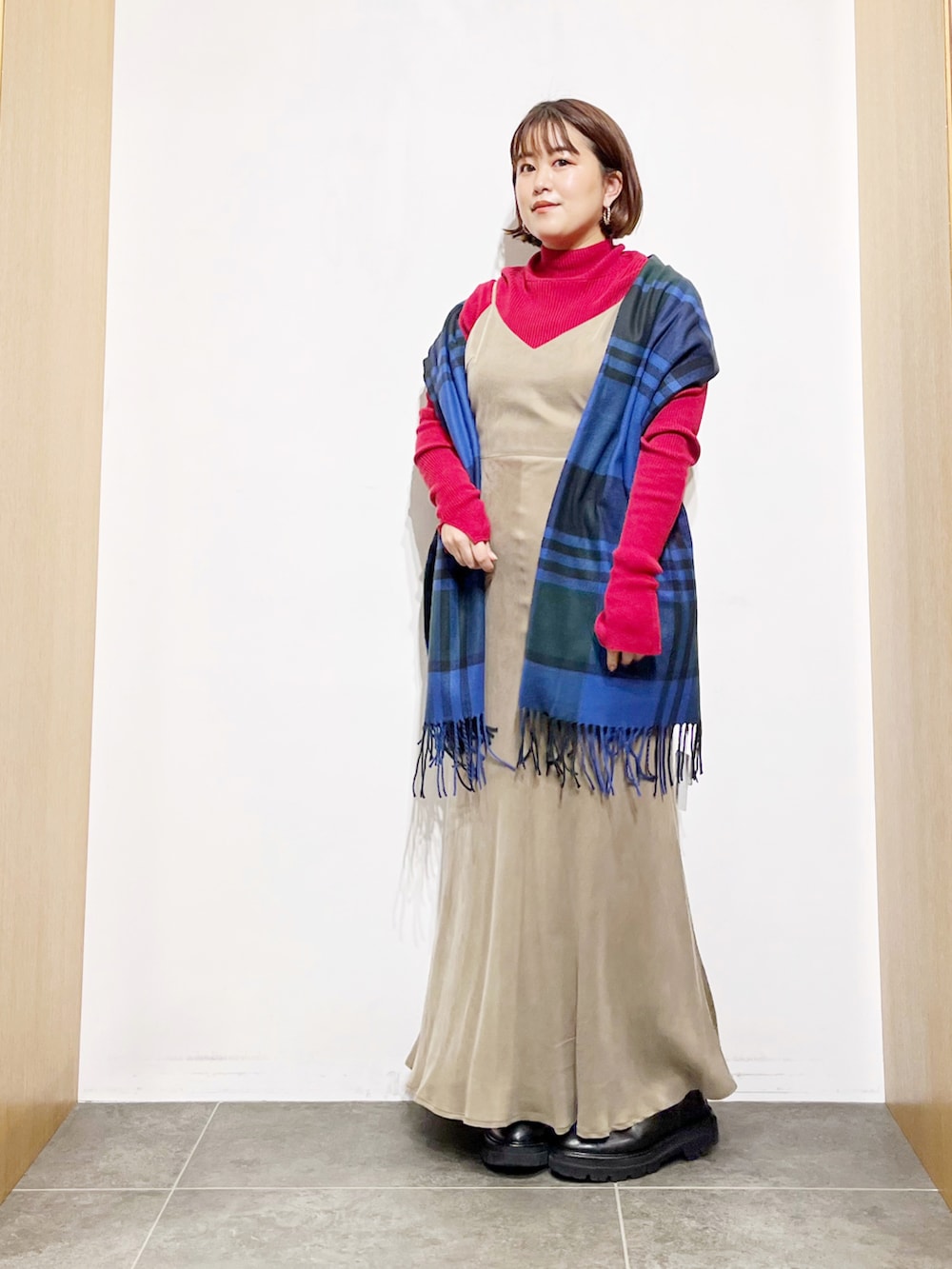 ベージュ系のワンピース、ブラック系のブーツ、レッド系のニット/セーターを着用したレディースの冬コーディネートの3枚目の写真