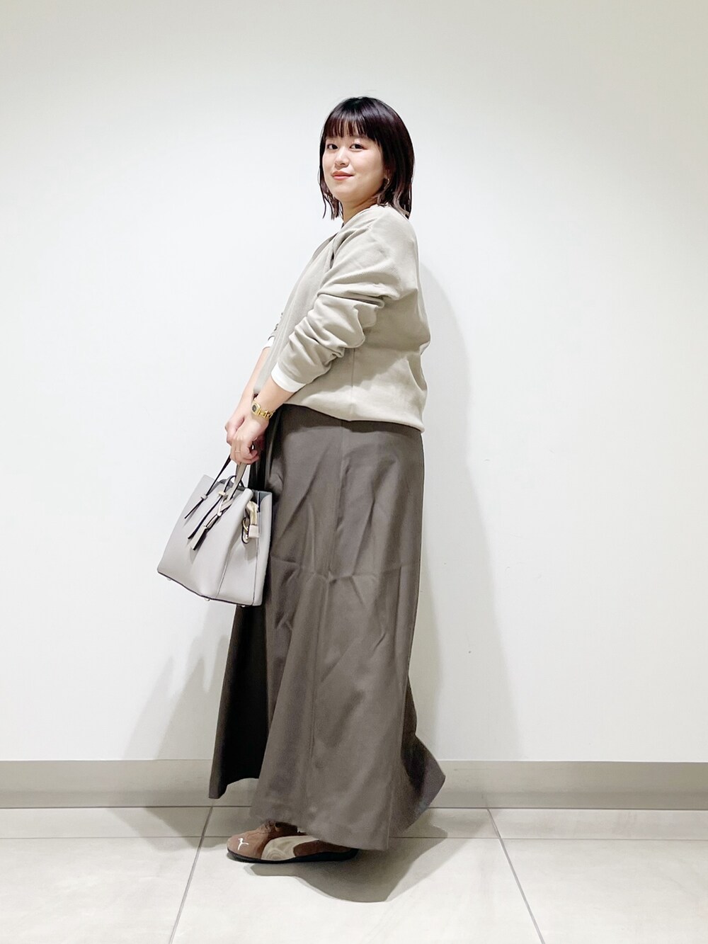 ベージュ系のTシャツ/カットソー、ブラウン系のスカート、グレー系のトートバッグを着用したレディースの秋コーディネートの5枚目の写真