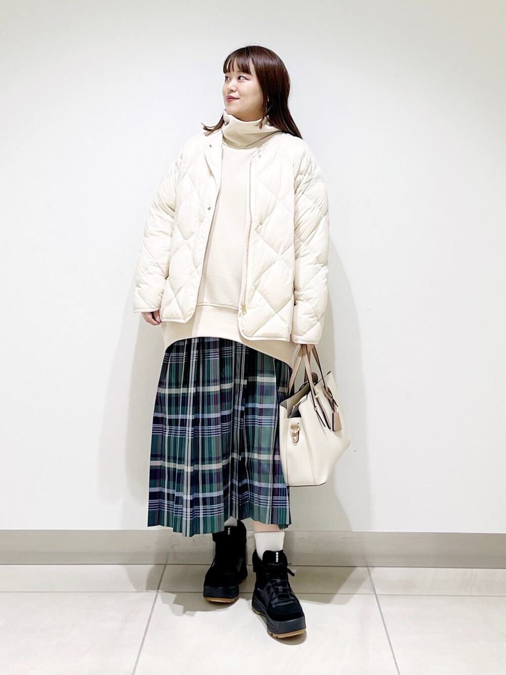 ベージュ系のスウェット、ホワイト系のダウンジャケット/コート、グリーン系のスカートを着用したレディースの秋コーディネートの10枚目の写真