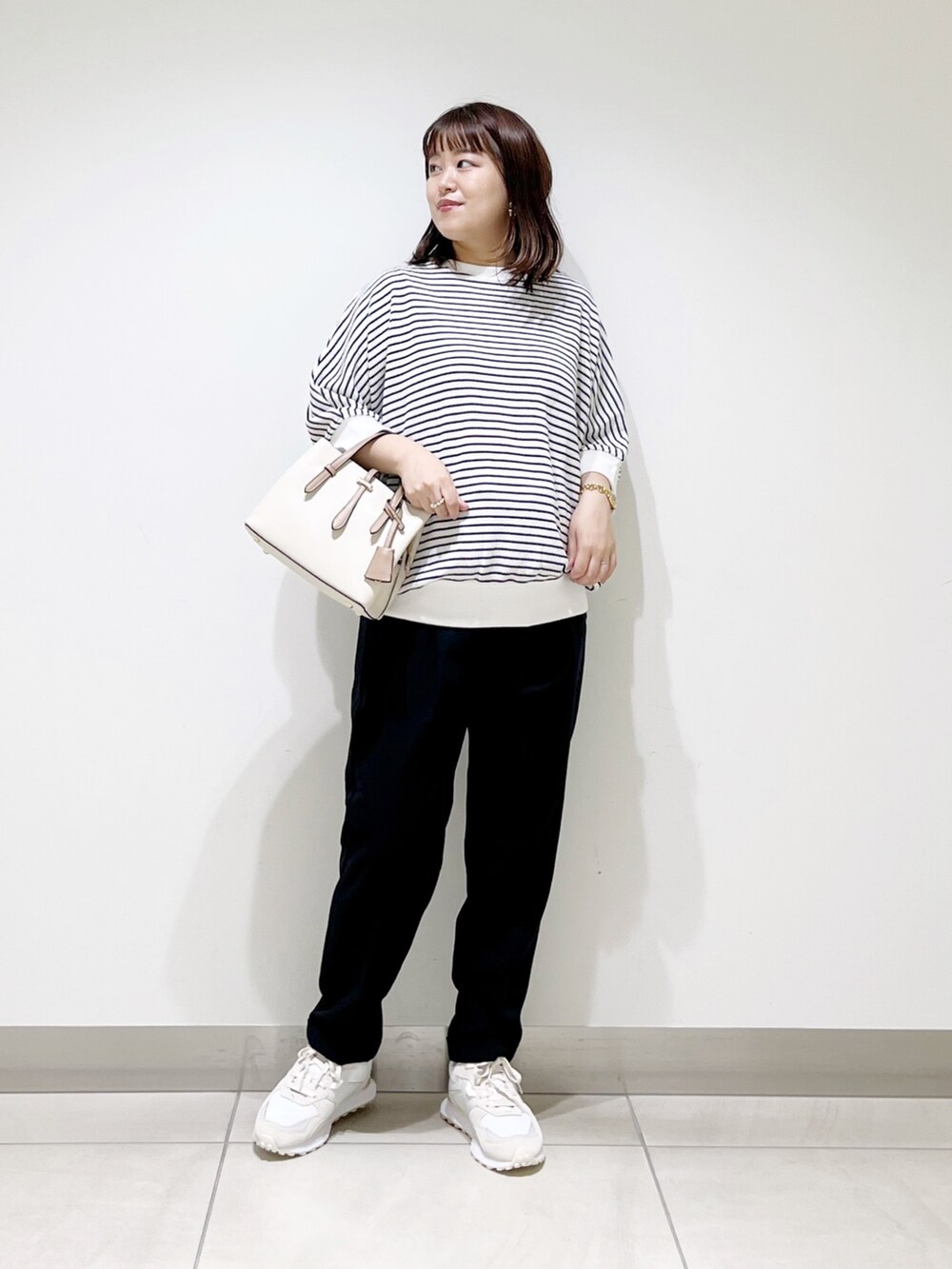 ホワイト系のTシャツ/カットソー、ブルー系のパンツ、ホワイト系のハンドバッグを着用したレディースの秋コーディネートの2枚目の写真