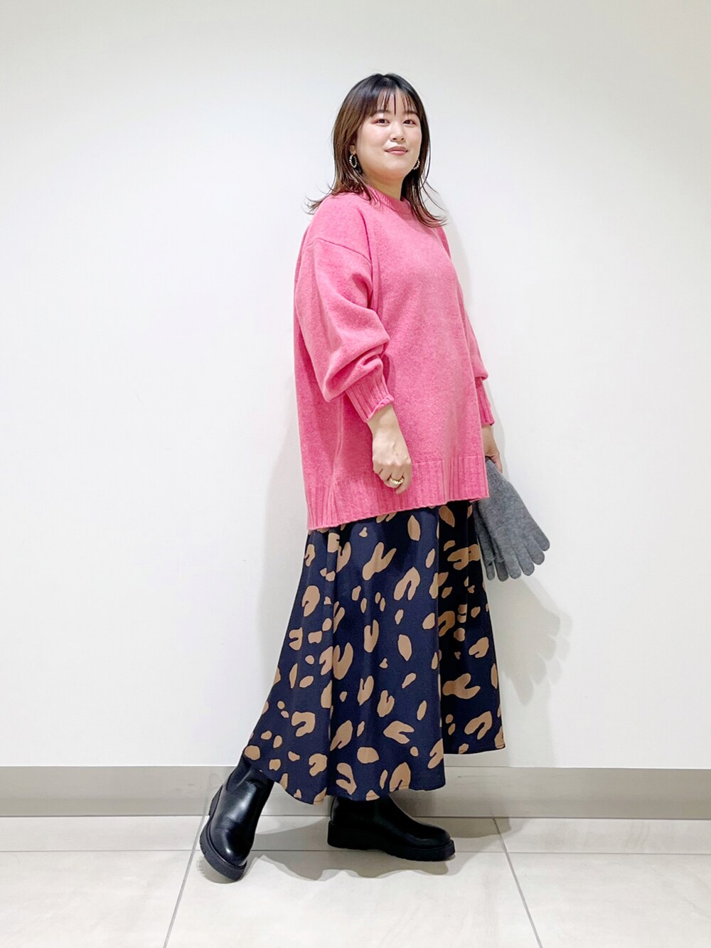ピンク系のニット/セーター、ブルー系のスカート、ブラック系のブーツを着用したレディースの秋コーディネートの4枚目の写真