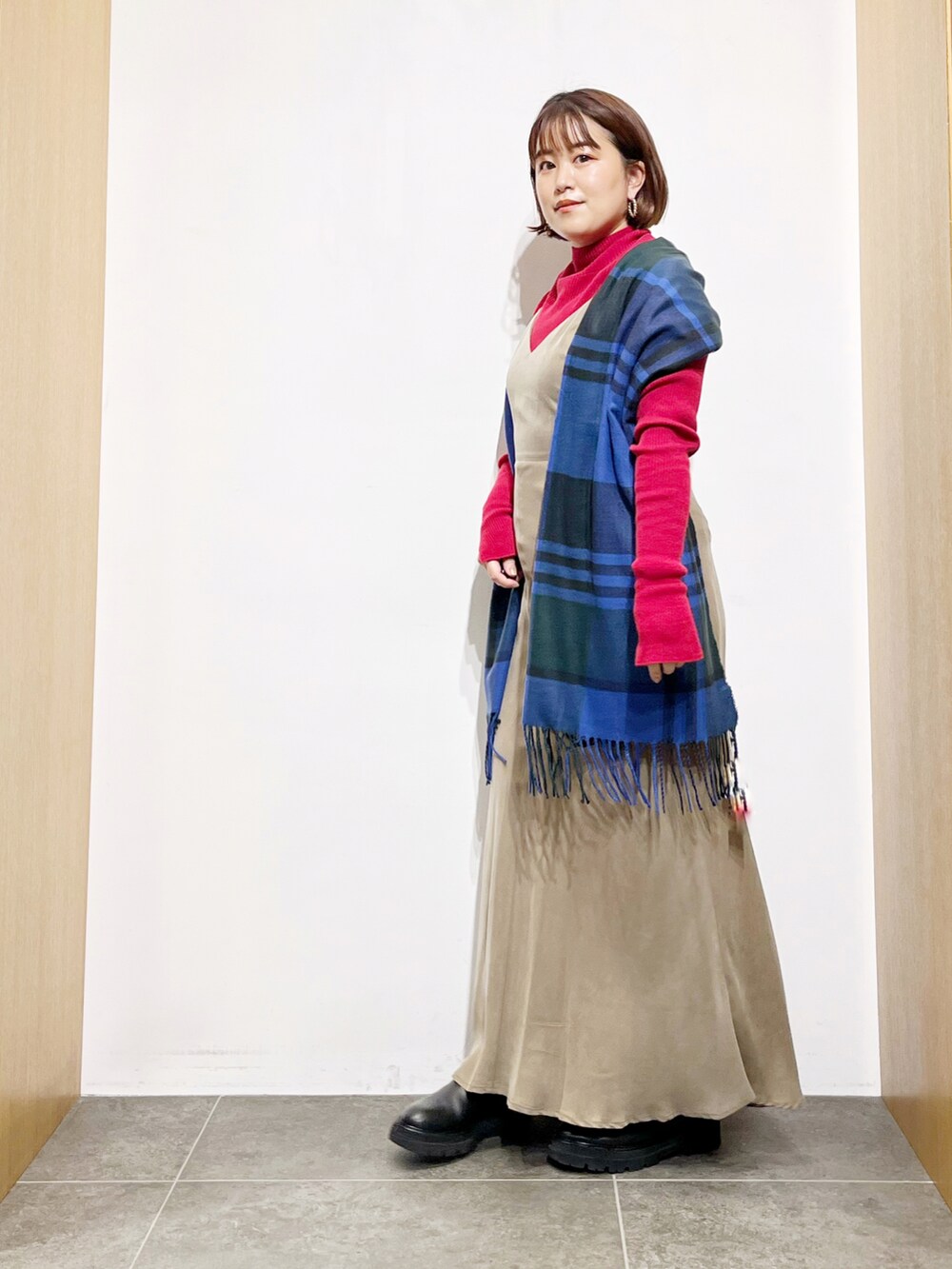 ベージュ系のワンピース、ブラック系のブーツ、レッド系のニット/セーターを着用したレディースの冬コーディネートの2枚目の写真