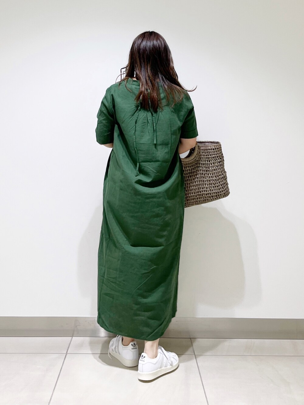 グリーン系のワンピース、グレー系のかごバッグ、ホワイト系のスニーカーを着用したレディースの夏コーディネートの3枚目の写真