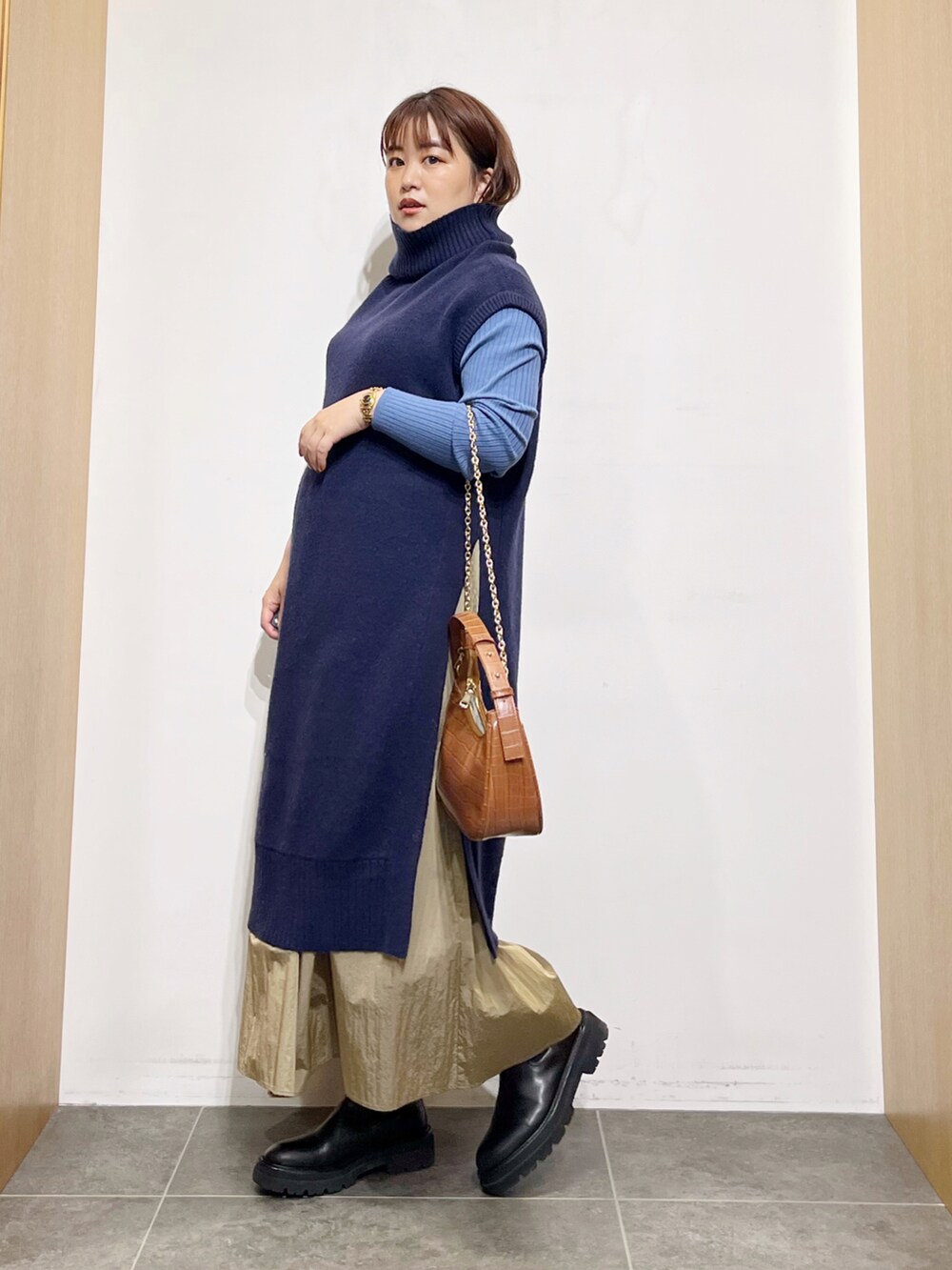 ブルー系のワンピース、ブラック系のブーツ、ベージュ系のスカートを着用したレディースの秋コーディネートの2枚目の写真