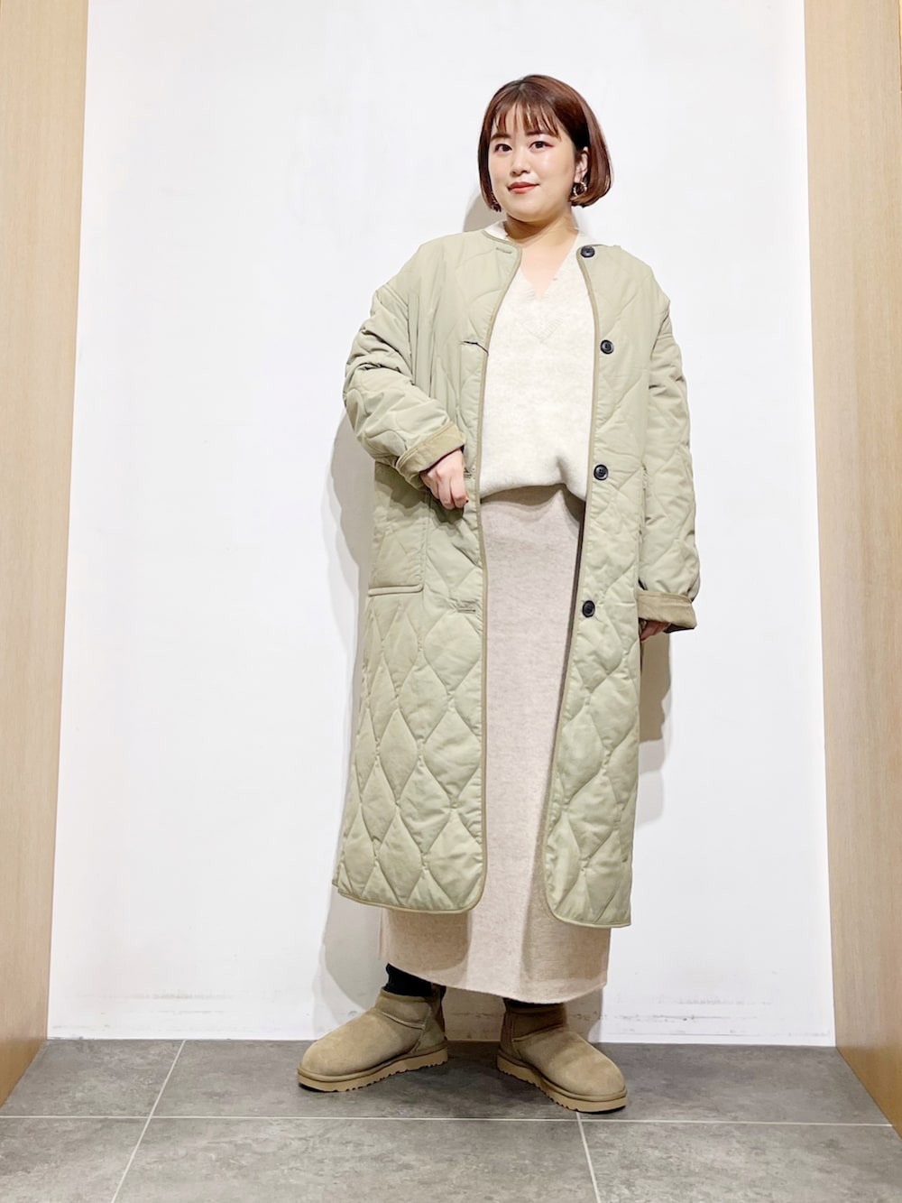 グリーン系のその他アウター、ベージュ系のスカート、グリーン系のブーツを着用したレディースの秋コーディネートの2枚目の写真