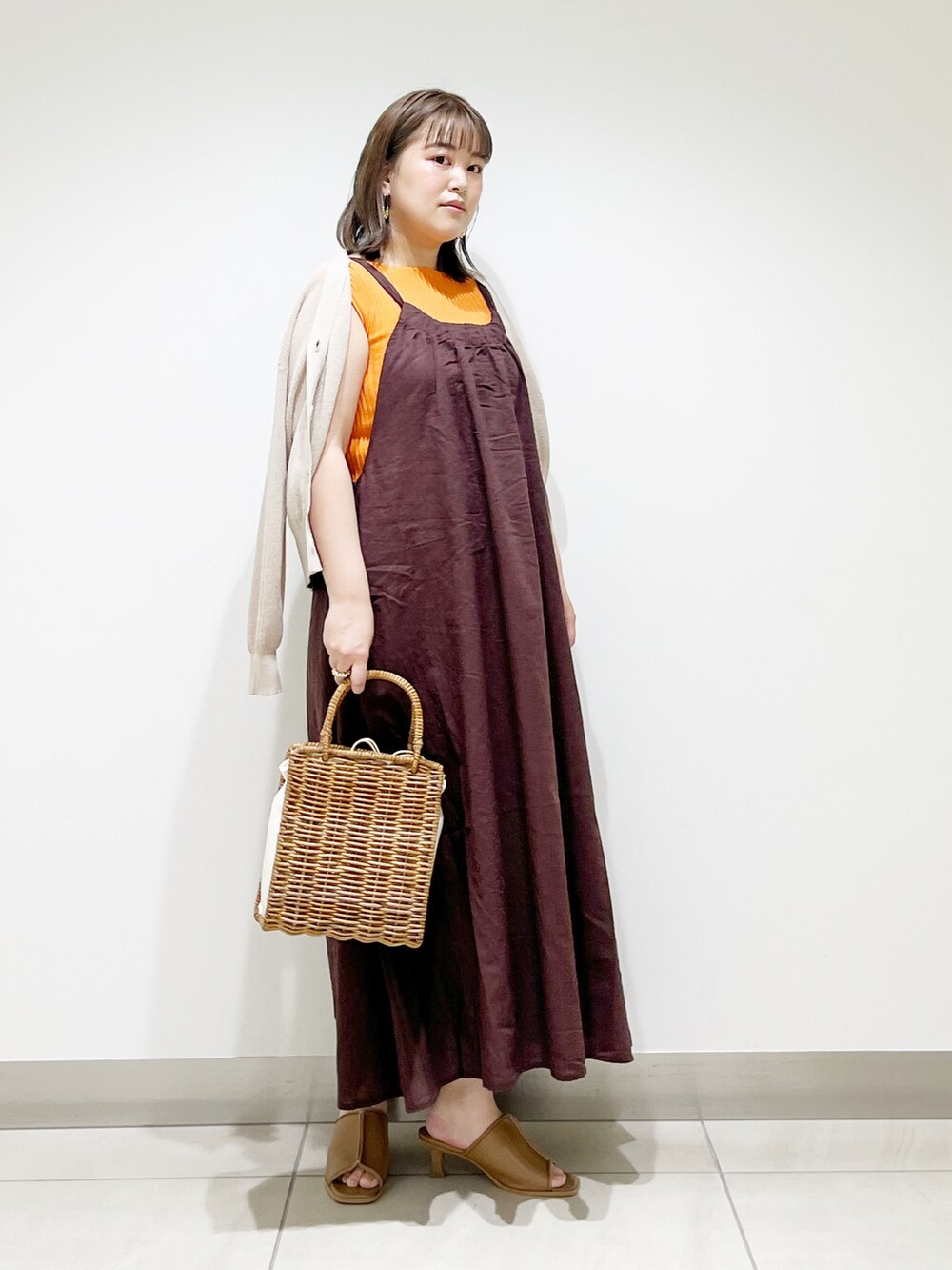 ブラウン系のワンピース、オレンジ系のニット/セーター、ホワイト系のハンドバッグを着用したレディースの春コーディネートの5枚目の写真