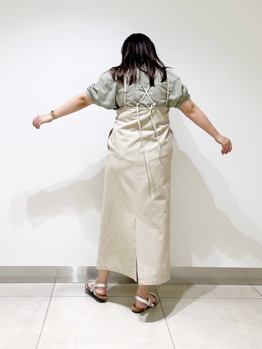 ベージュ系のワンピース、シルバー系のサンダル、グリーン系のTシャツ/カットソーを着用したレディースの春コーディネートの3枚目の写真