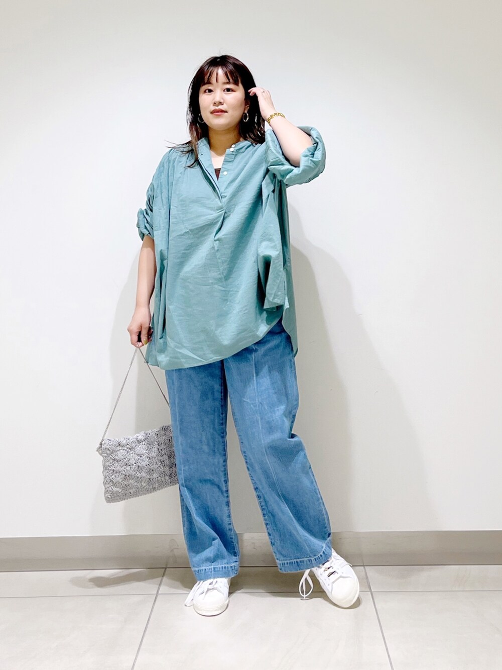 グリーン系のシャツ/ブラウス、ブルー系のデニムパンツ、シルバー系のバッグを着用したレディースの春コーディネートの3枚目の写真