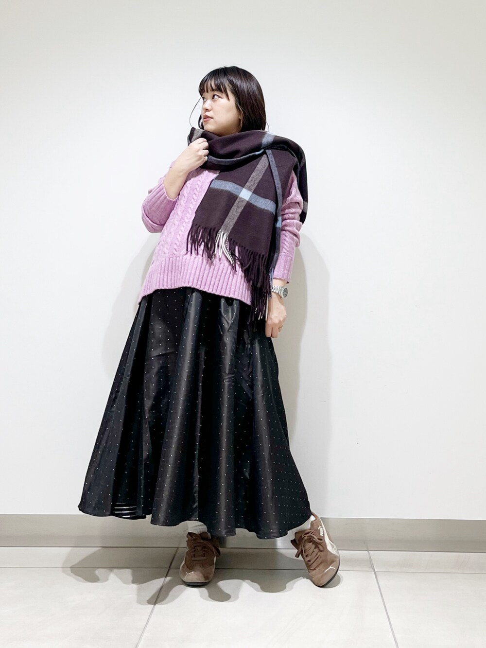 パープル系のニット/セーター、ブルー系のスカート、ブラック系のスニーカーを着用したレディースの秋コーディネートの2枚目の写真