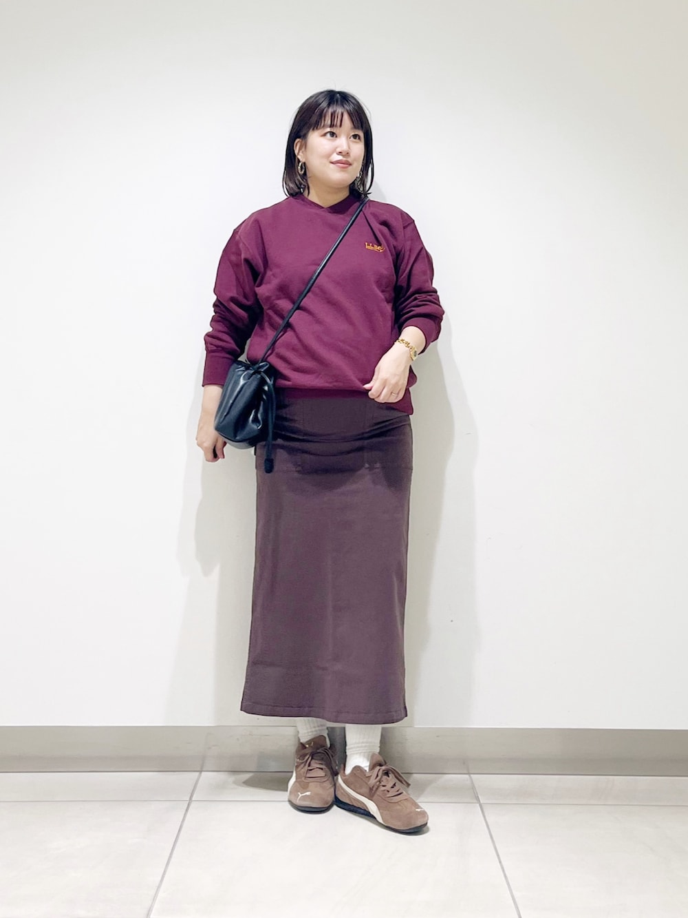 ブラウン系のスウェット、ブラウン系のスカート、ブラック系のスニーカーを着用したレディースの秋コーディネートの9枚目の写真