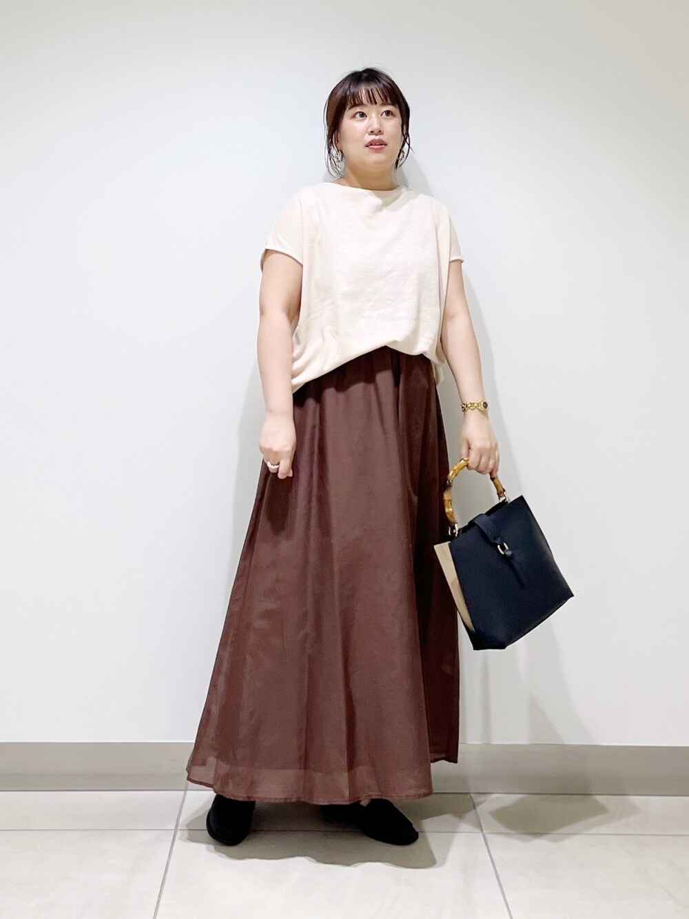ベージュ系のTシャツ/カットソー、ブラウン系のスカート、ブラック系のハンドバッグを着用したレディースの夏コーディネートの5枚目の写真