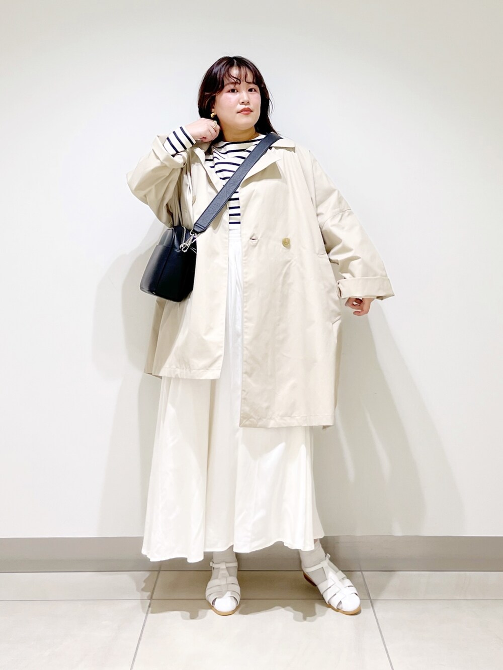 ベージュ系のポンチョ、ホワイト系のTシャツ/カットソー、ホワイト系のスカートを着用したレディースの春コーディネートの4枚目の写真
