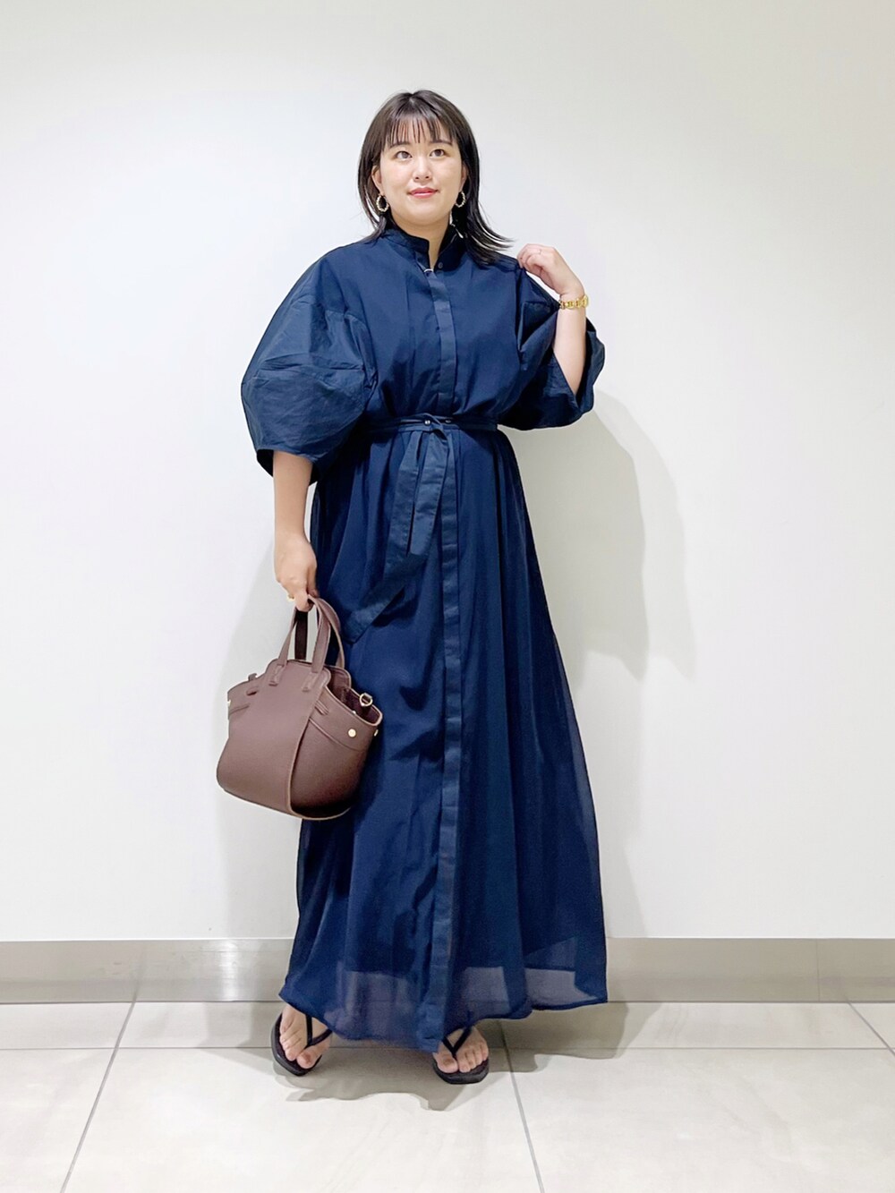 ブルー系のワンピース、ブラウン系のハンドバッグ、ブラック系のサンダルを着用したレディースの夏コーディネートの2枚目の写真