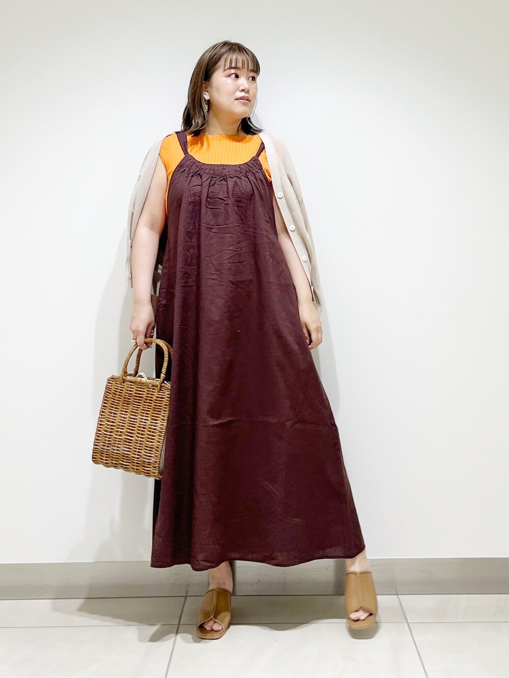 ブラウン系のワンピース、オレンジ系のニット/セーター、ホワイト系のハンドバッグを着用したレディースの春コーディネートの3枚目の写真