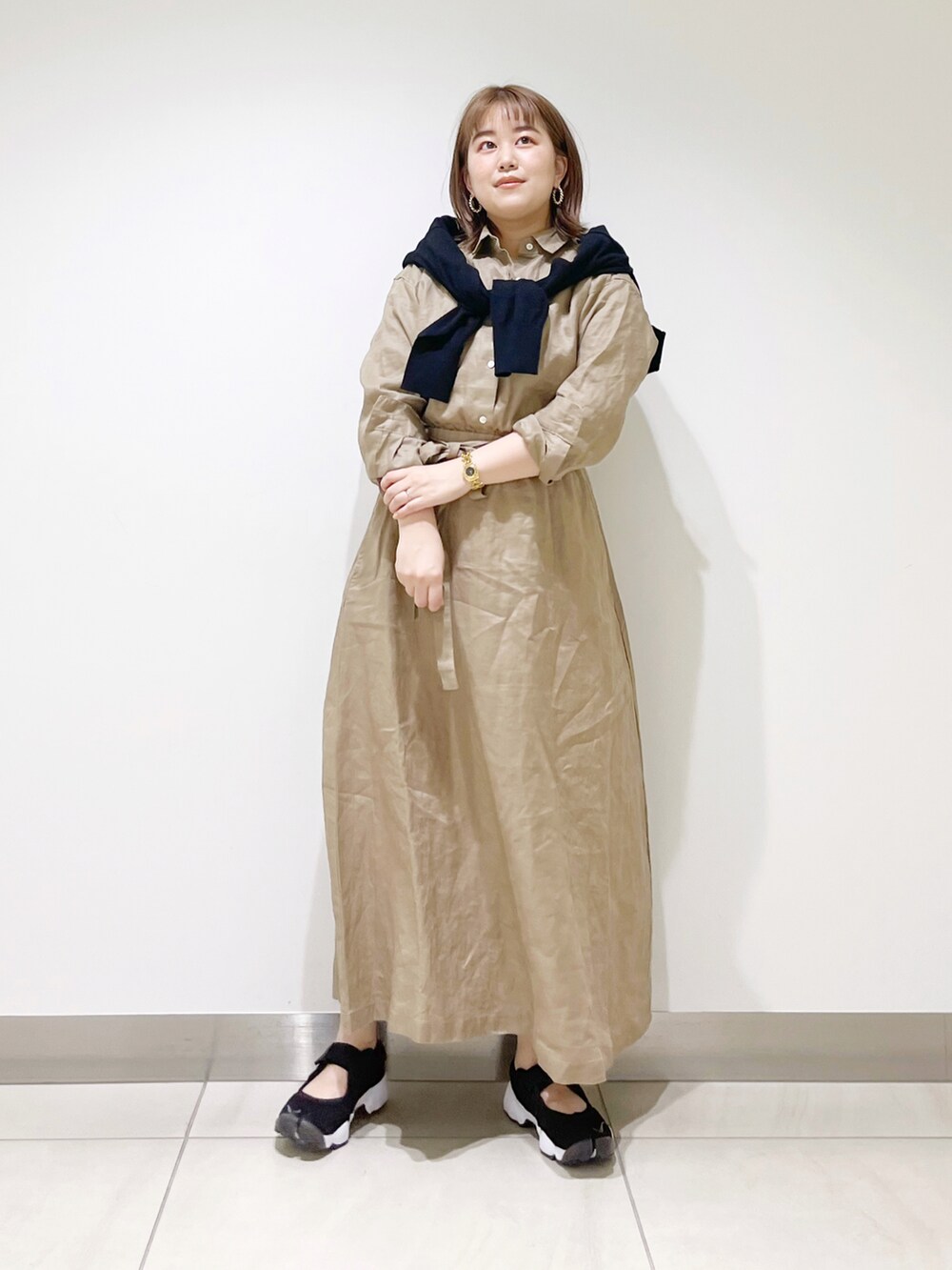 ベージュ系のワンピース、ブラック系のカーディガン/ボレロ、ブラック系のスニーカーを着用したレディースの春コーディネートの3枚目の写真