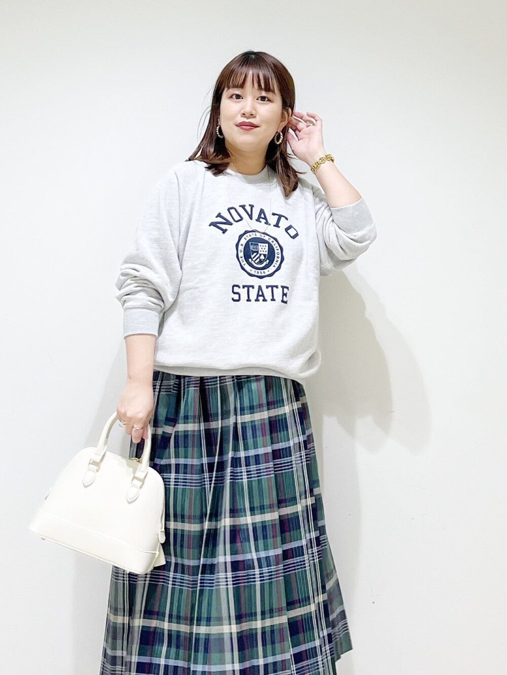 グリーン系のスカート、グレー系のスウェット、ホワイト系のショルダーバッグを着用したレディースの冬コーディネートの5枚目の写真