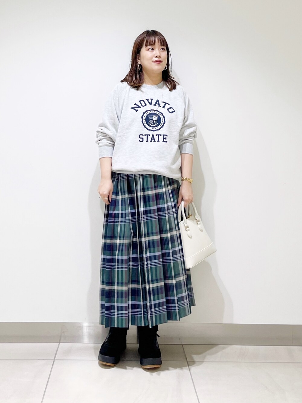 グリーン系のスカート、グレー系のスウェット、ホワイト系のショルダーバッグを着用したレディースの冬コーディネートの6枚目の写真