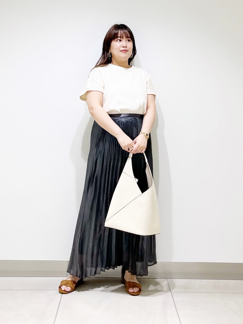 ブラック系のスカート、ホワイト系のニット/セーター、ホワイト系のトートバッグを着用したレディースの夏コーディネートの3枚目の写真