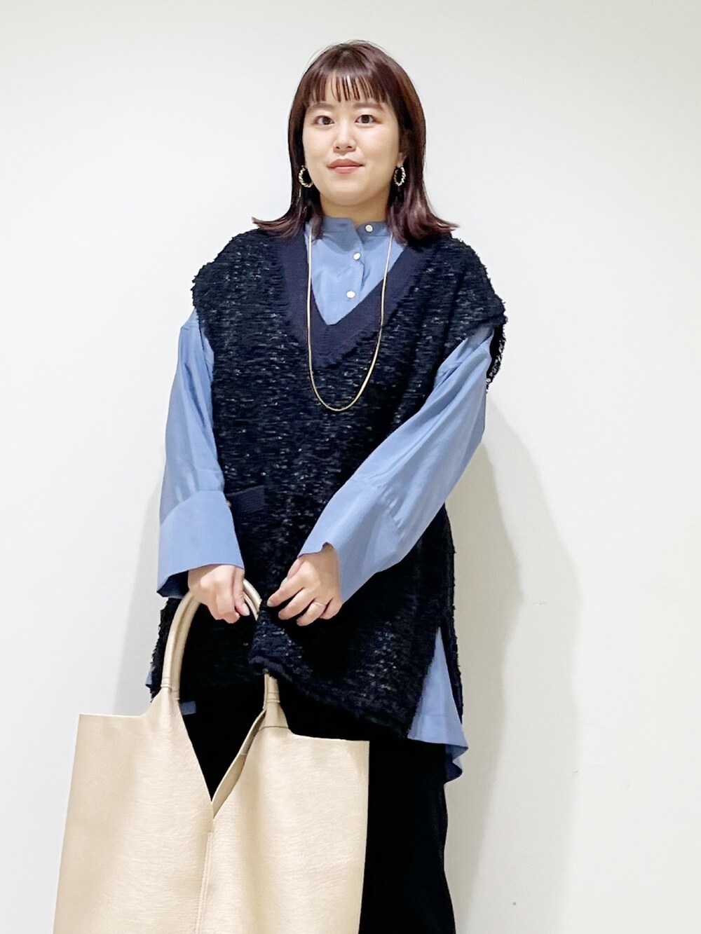 ブルー系のシャツ/ブラウス、ブラック系のスカート、ゴールド系のトートバッグを着用したレディースの秋コーディネートの6枚目の写真