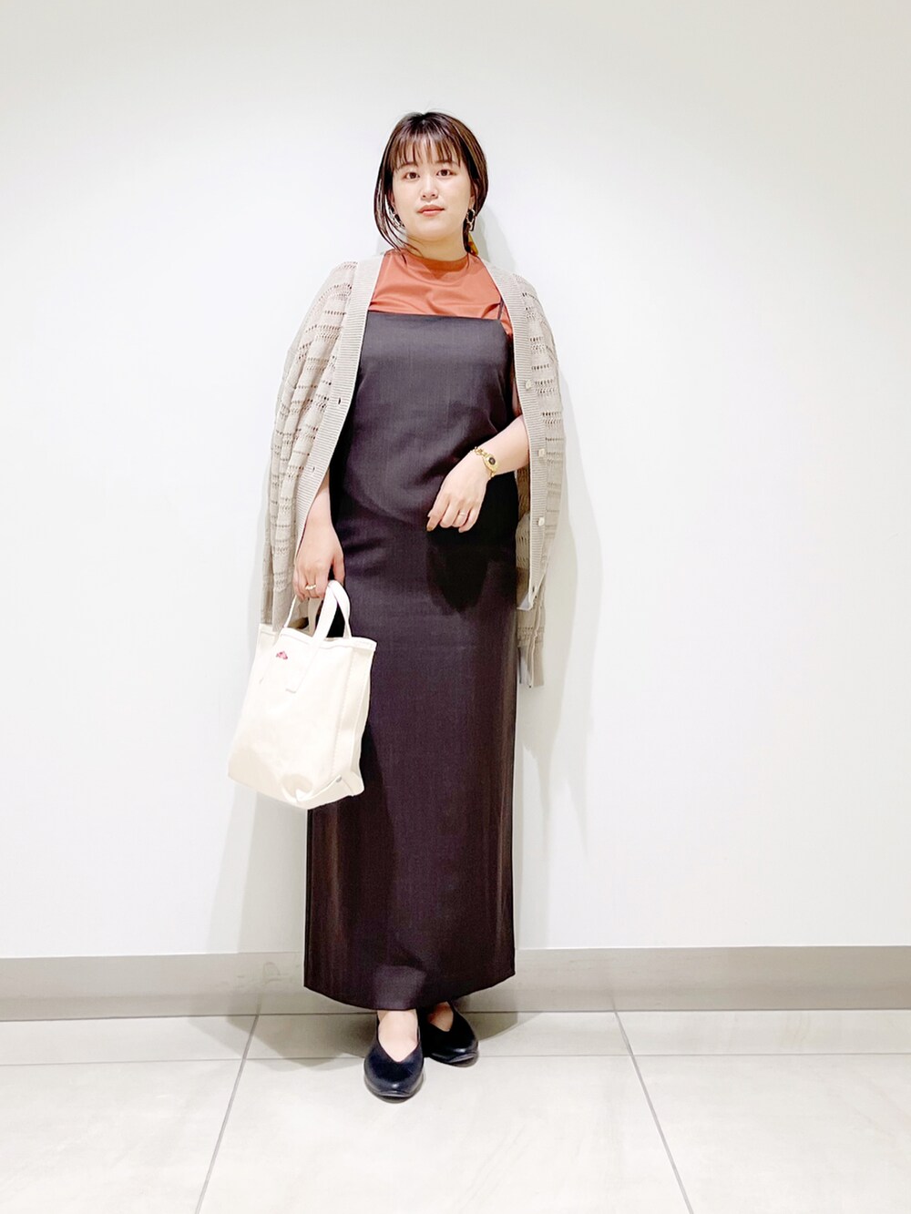 グレー系のワンピース、ホワイト系のトートバッグ、ブラック系のパンプスを着用したレディースの夏コーディネートの3枚目の写真