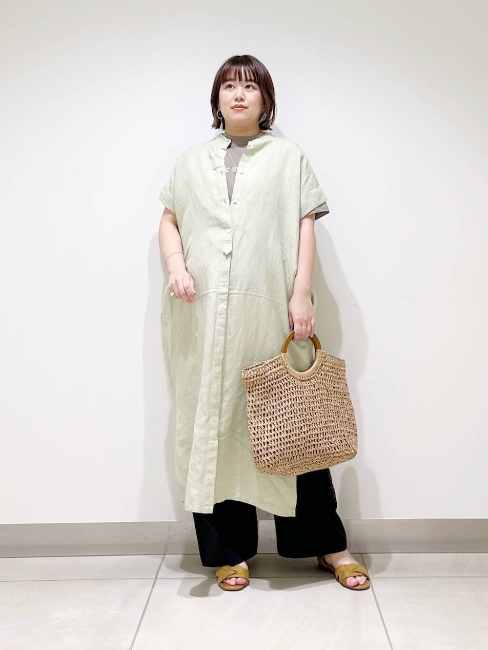 ブラック系のその他パンツ、グリーン系のワンピース、ベージュ系のトートバッグを着用したレディースの春コーディネートの2枚目の写真